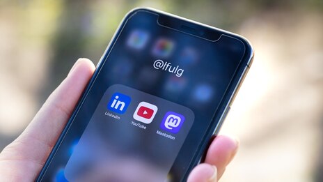 Hand hält Smartphone mit Icons von Socialmedia-Software
